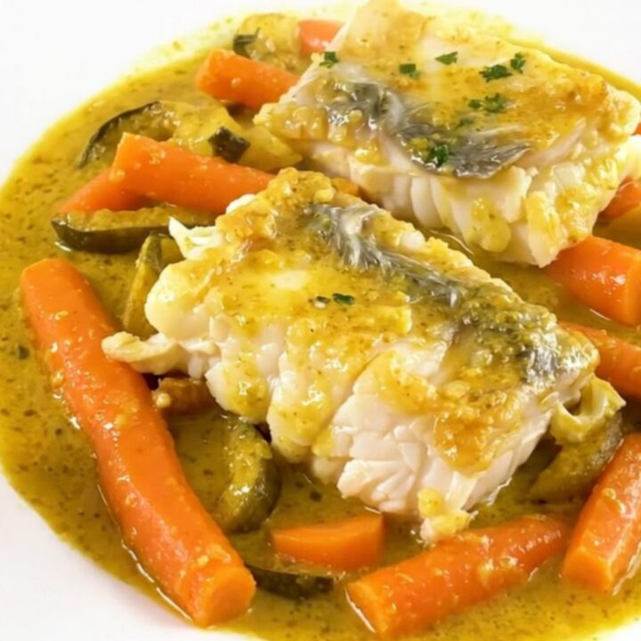 A top-down view of raw haddock fillets, sliced carrots, and onions in a slow cooker.