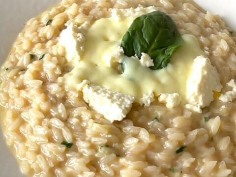 Risotto crémeux aux épinards et chèvre servi dans une assiette blanche avec une vapeur légère.