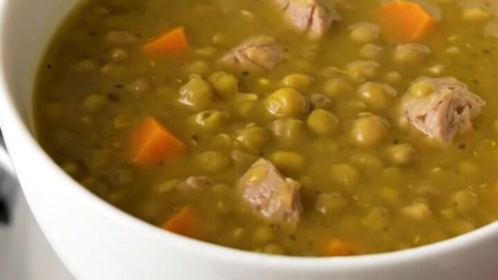 A steaming bowl of split pea and smoked sausage soup with visible sausage rounds and diced carrots.