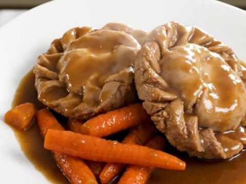 Paupiettes de veau dorées mijotées avec des rondelles de carottes fondantes dans une sauce onctueuse.