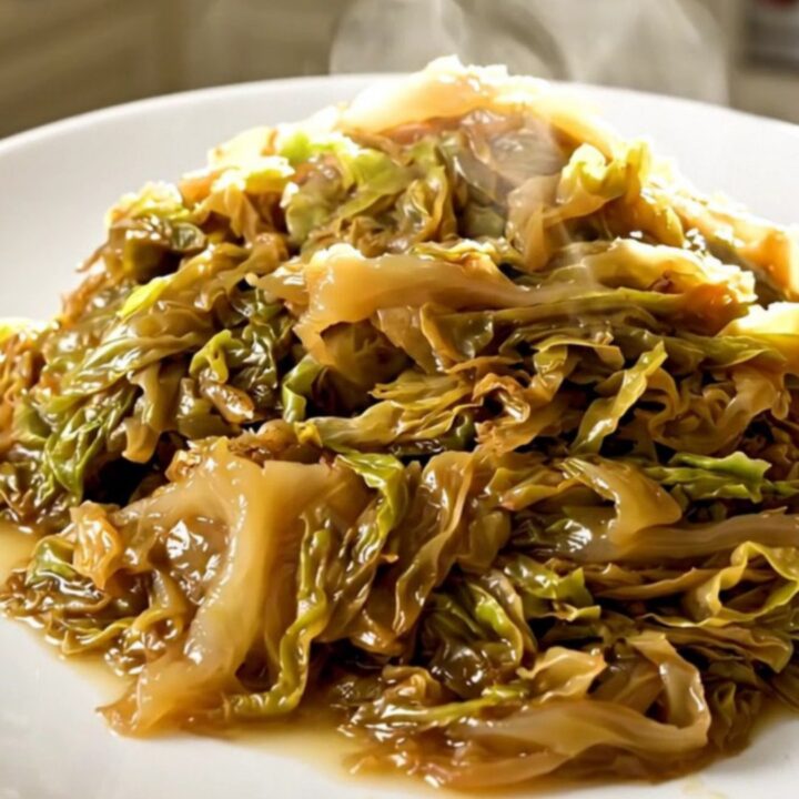 A top-down view of a black slow cooker filled with layers of sliced onions and shredded green cabbage.
