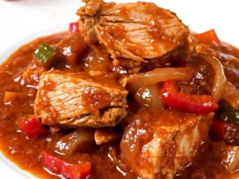 A slow cooker filled with a vibrant red turkey and bell pepper stew.