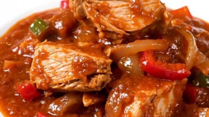 A slow cooker filled with a vibrant red turkey and bell pepper stew.
