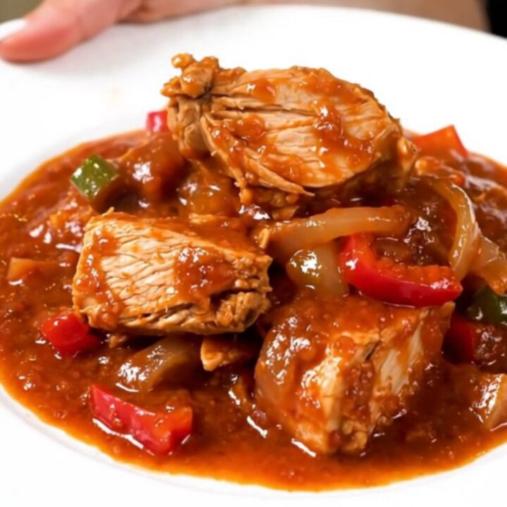 A slow cooker filled with a vibrant red turkey and bell pepper stew.