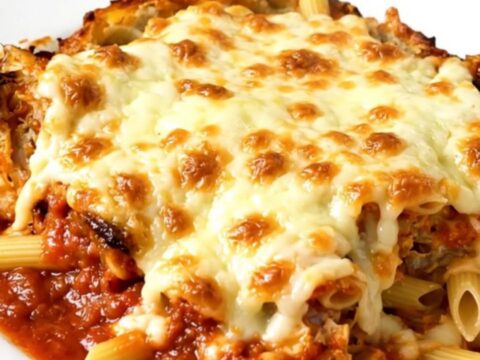A steaming, cheesy slow cooker chicken penne bake served on a white plate.