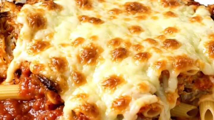 A steaming, cheesy slow cooker chicken penne bake served on a white plate.