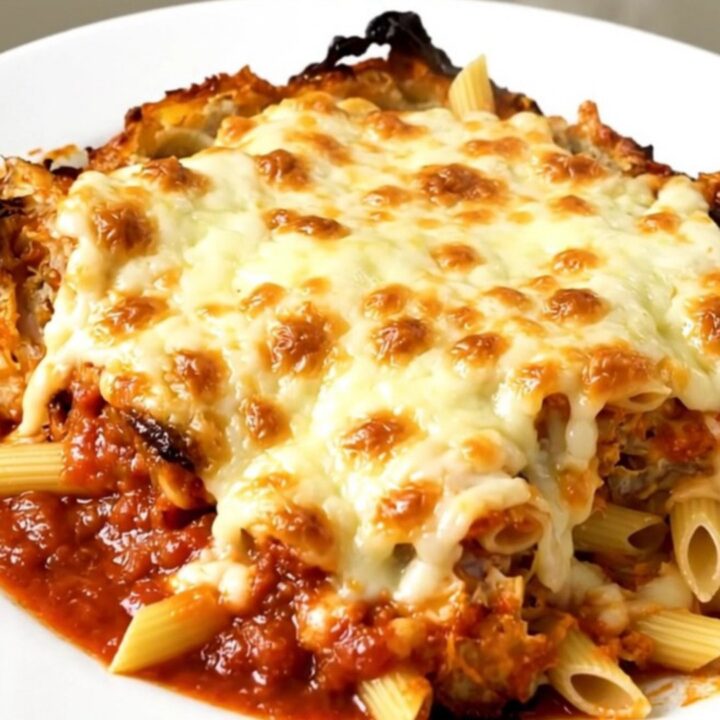 A steaming, cheesy slow cooker chicken penne bake served on a white plate.
