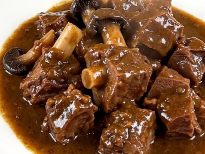 A close-up of a steaming, glossy slow cooker lamb navarin served on a white plate.