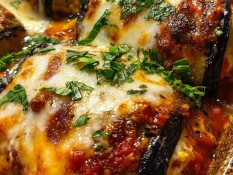 A fork lifting a tender eggplant roll with a long, appetizing stretch of melted mozzarella cheese and steam.