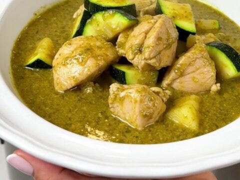 A steaming bowl of creamy green chicken curry with zucchini slices and a rich coconut milk sauce.