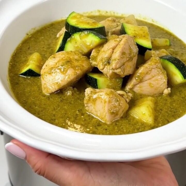 A steaming bowl of creamy green chicken curry with zucchini slices and a rich coconut milk sauce.