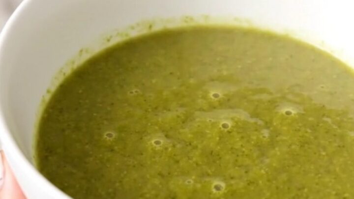 A white bowl filled with creamy green broccoli soup, garnished with a crumble of Roquefort cheese.