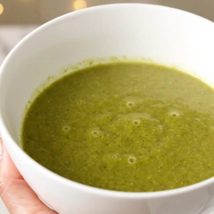A white bowl filled with creamy green broccoli soup, garnished with a crumble of Roquefort cheese.