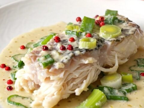 Filets de lingue cuits dans une sauce crémeuse aux poireaux, servis sur une assiette blanche.