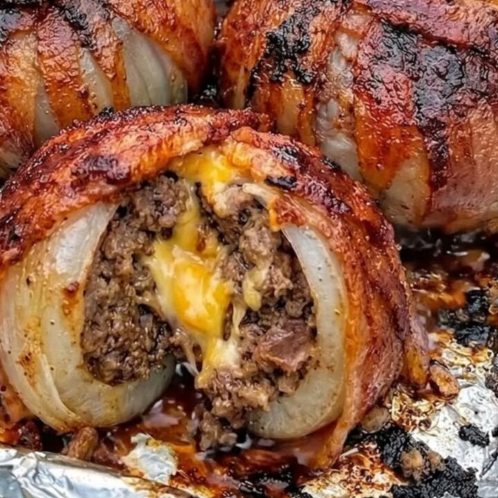 A close-up of a crispy bacon-wrapped onion bomb cut open to reveal juicy ground beef and melted cheddar cheese.