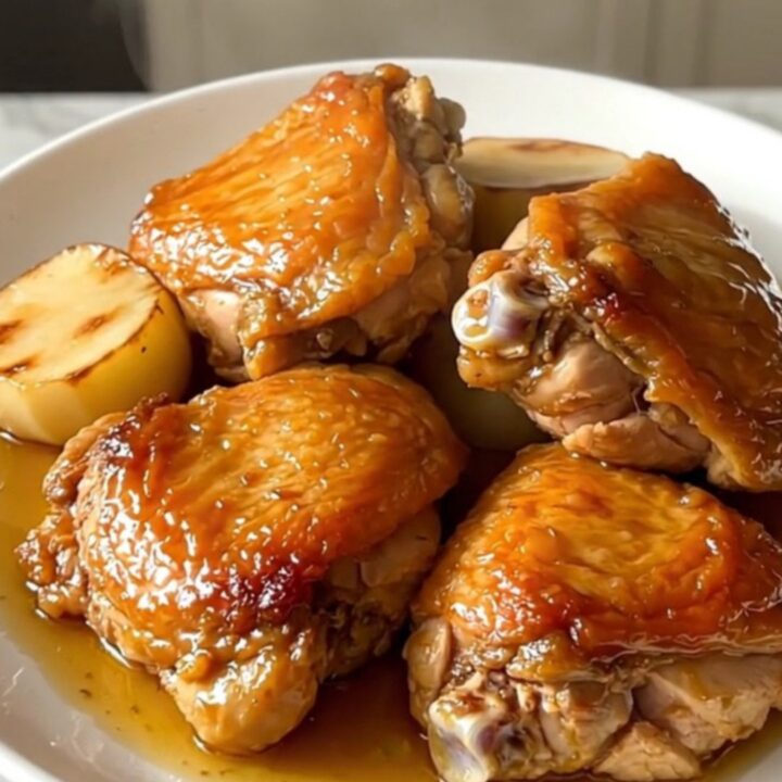 Slow cooker honey glazed chicken thighs with tender turnips on a white plate.