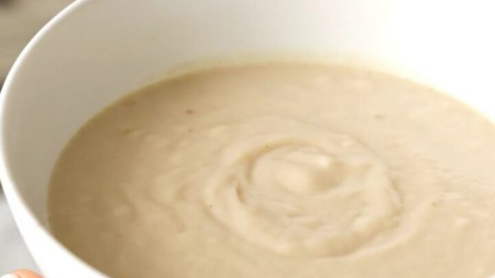 A white bowl filled with creamy, steaming parsnip and pear velouté, showcasing its smooth and elegant texture.