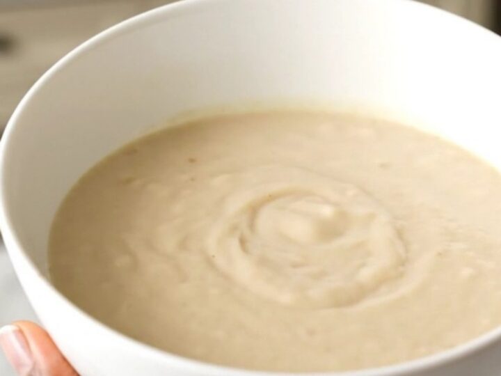 A white bowl filled with creamy, steaming parsnip and pear velouté, showcasing its smooth and elegant texture.