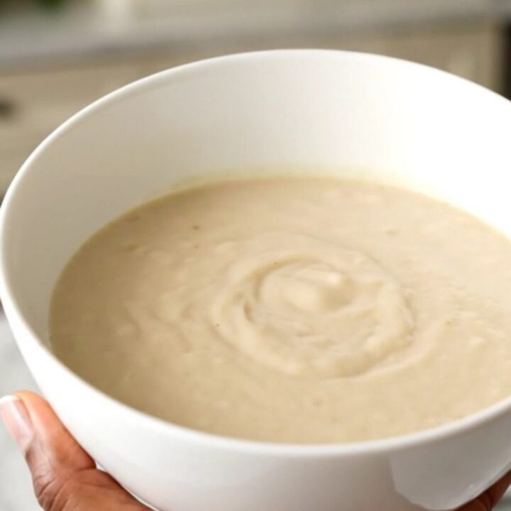 A white bowl filled with creamy, steaming parsnip and pear velouté, showcasing its smooth and elegant texture.