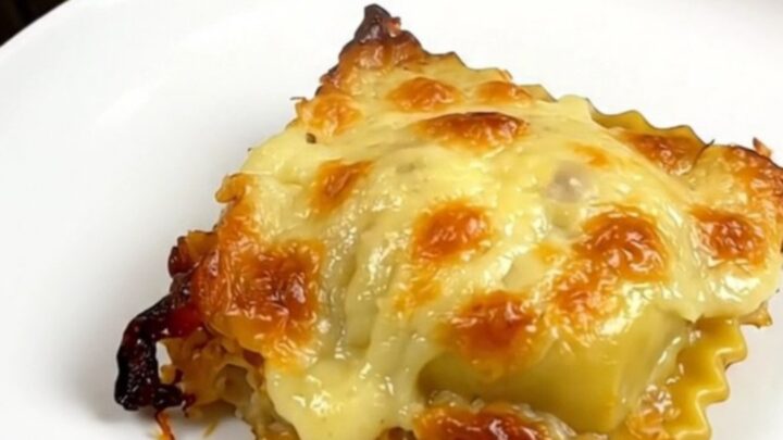 A top-down view of a slow cooker filled with layers of ravioli, ham, and melted Comté cheese.