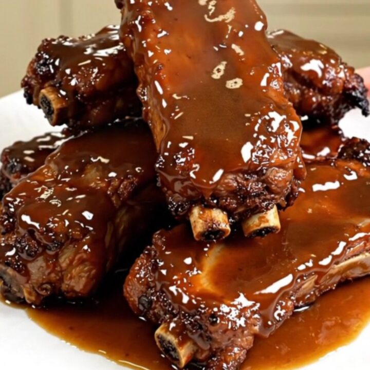 A close-up of tender, glazed maple mustard pork ribs served on a clean white plate.