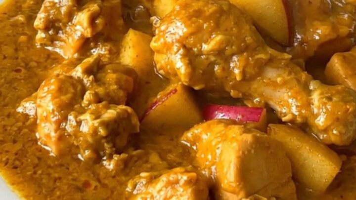 A top-down view of a slow cooker filled with chicken, apples, and onions before cooking.