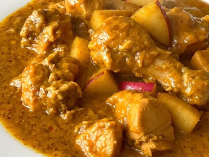 A top-down view of a slow cooker filled with chicken, apples, and onions before cooking.