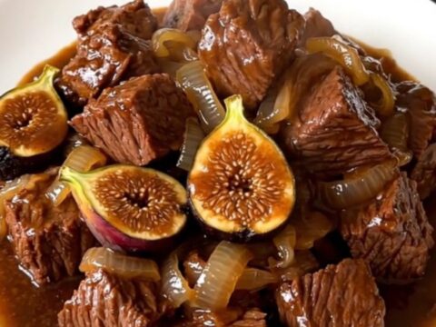 Bœuf mijoté à la corse avec des figues, servi dans une assiette blanche, montrant une viande tendre et une sauce brillante.