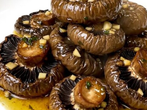 A top-down view of garlic and herb portobello mushrooms cooking in a slow cooker.
