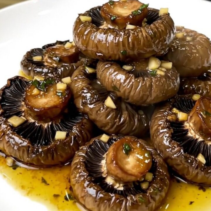 A top-down view of garlic and herb portobello mushrooms cooking in a slow cooker.