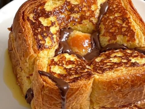A close-up of the slow cooker filled with golden-brown brioche French toast topped with pears and chocolate.