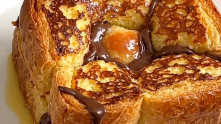 A close-up of the slow cooker filled with golden-brown brioche French toast topped with pears and chocolate.