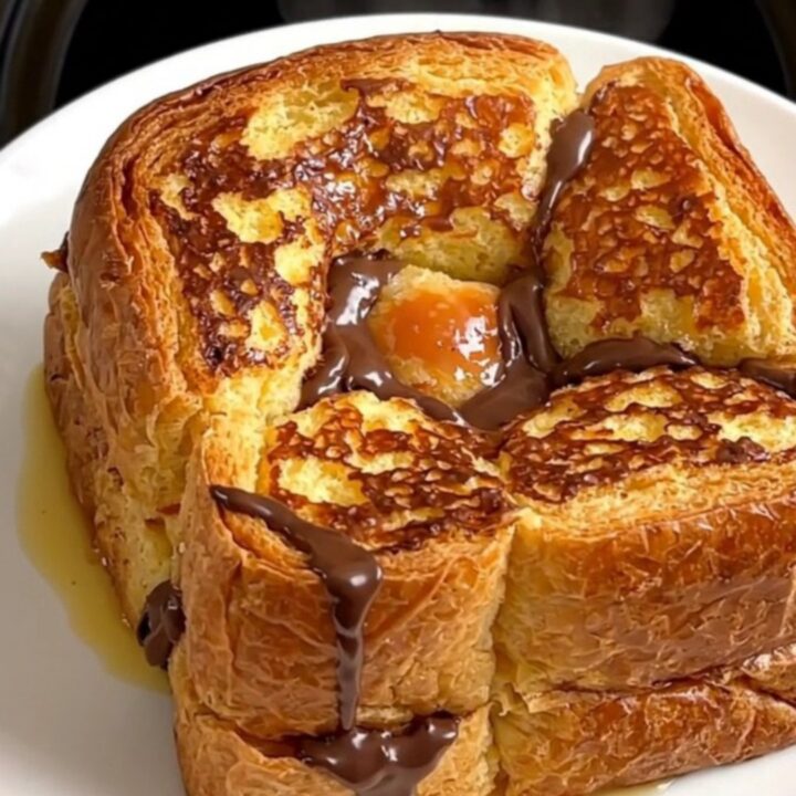 A close-up of the slow cooker filled with golden-brown brioche French toast topped with pears and chocolate.