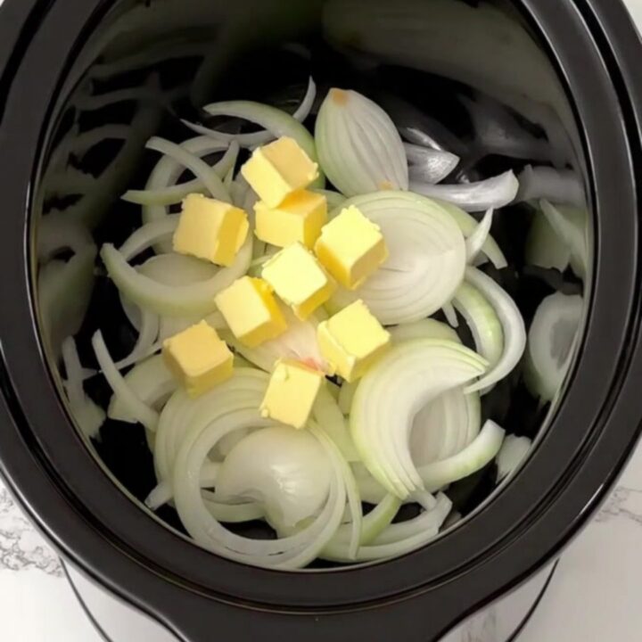A slow cooker filled with golden, caramelized onions and broth, ready to be served as a comforting meal.