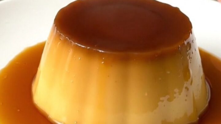 A finished coffee crème caramel unmolded on a white plate with glossy amber syrup.
