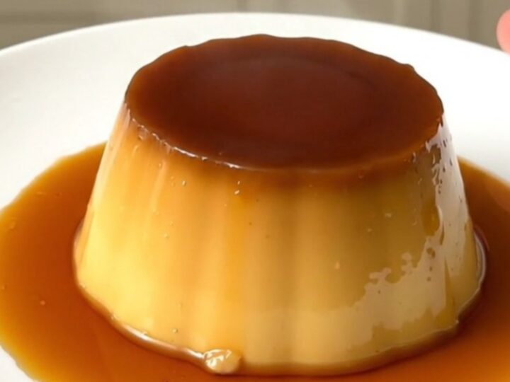 A finished coffee crème caramel unmolded on a white plate with glossy amber syrup.