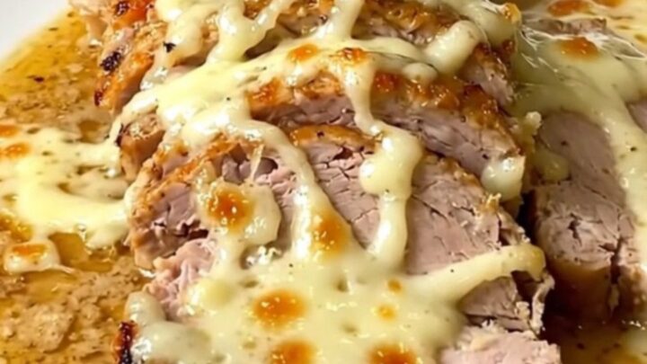 A plate of sliced, tender pork loin covered in a creamy white sauce on a white plate.