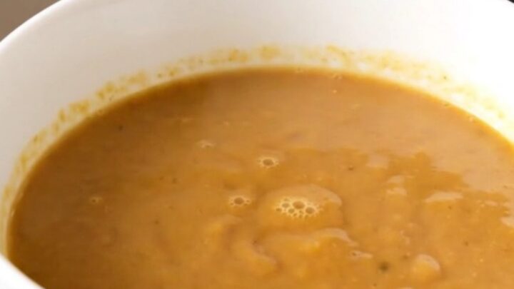 A close-up of a creamy, light-brown chestnut and porcini velouté served in a white ceramic bowl.