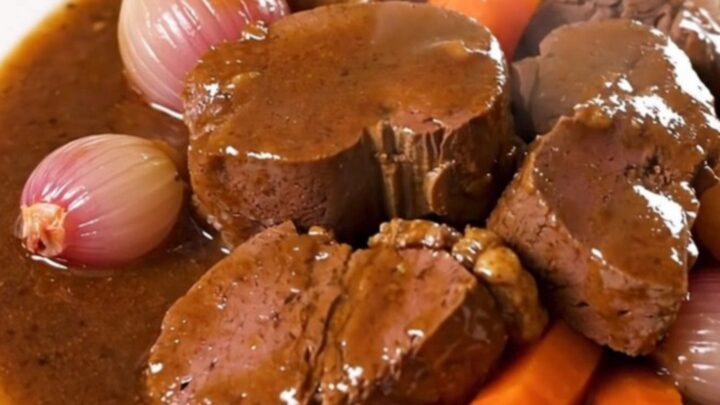 A glossy, rich Bordelaise veal stew served on a white plate with visible carrots and shallots.