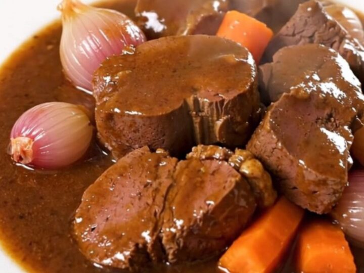 A glossy, rich Bordelaise veal stew served on a white plate with visible carrots and shallots.