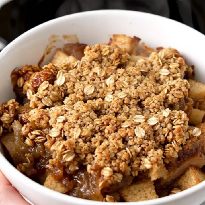 A top-down view of a slow cooker filled with diced apples, oats, cinnamon, and butter cubes ready to cook.