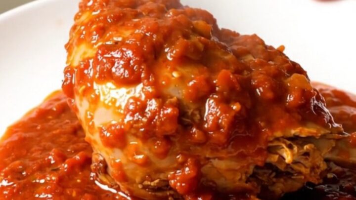 Two tender turkey drumsticks smothered in a rich, glossy tomato oregano sauce on a white plate.