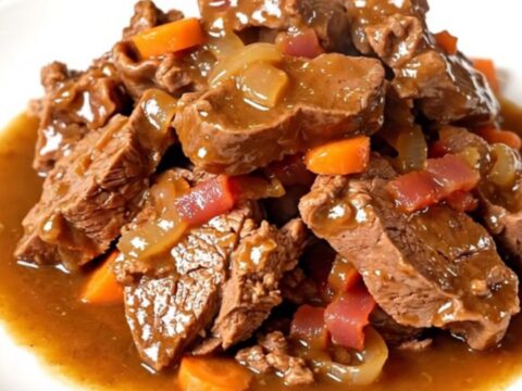 A rustic plate featuring tender slow-cooked veal tendrons topped with bacon, pearl onions