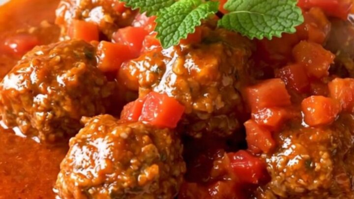 Steaming slow cooker beef meatball tagine coated in glossy tomato sauce with cumin and dried mint.