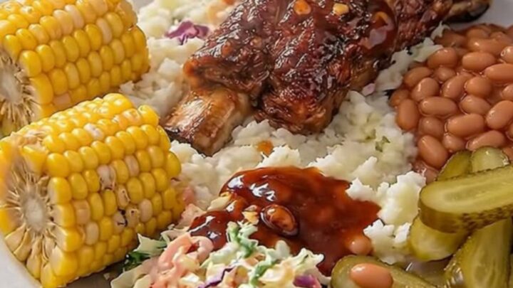 Sticky garlic BBQ ribs glistening under warm light on a rustic wooden board with side dishes.