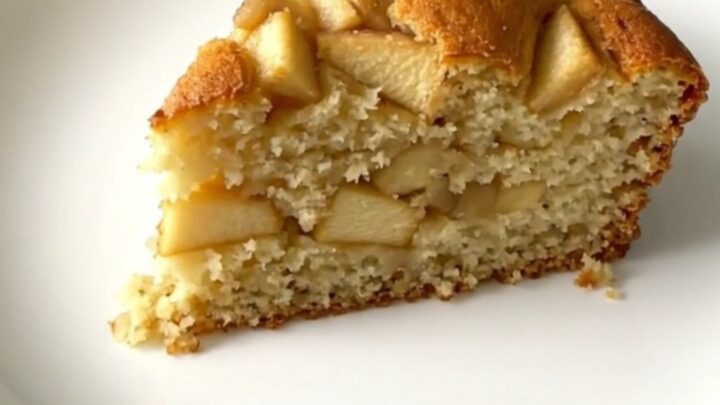 A golden, moist slice of apple yogurt cake served on a simple white plate.