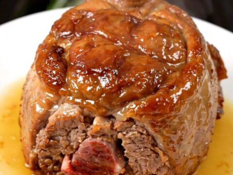 Succulent slow-cooked pork collar served on a white plate with fresh rosemary.