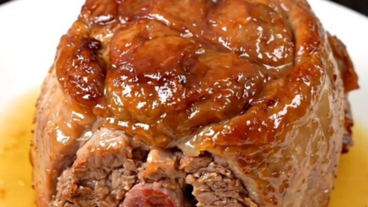 Succulent slow-cooked pork collar served on a white plate with fresh rosemary.