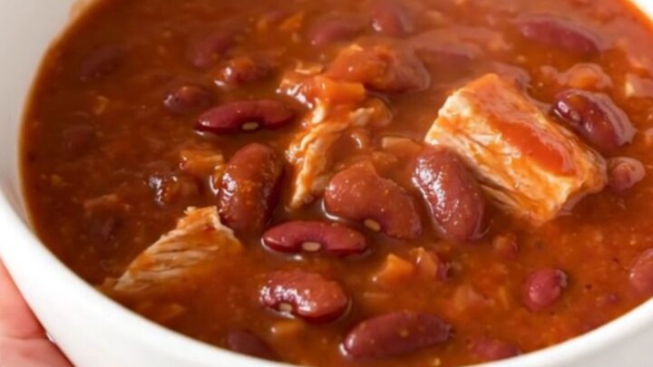 A steaming bowl of turkey chili with kidney beans and a rich tomato sauce, served in a white bowl.