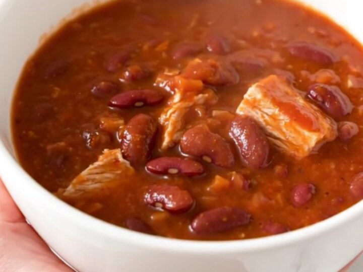 A steaming bowl of turkey chili with kidney beans and a rich tomato sauce, served in a white bowl.